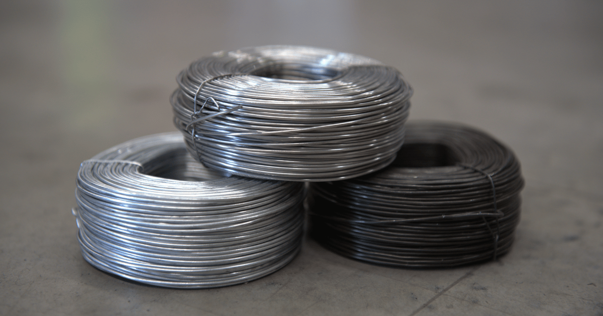 Three types of tie wire coils stacked together: black, galvanised, and stainless steel
